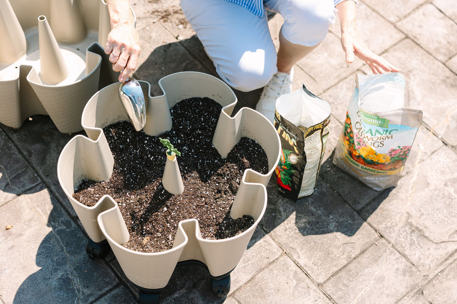 A woman is adding fertilizer amendments to her GreenStalk Vertical Planter
