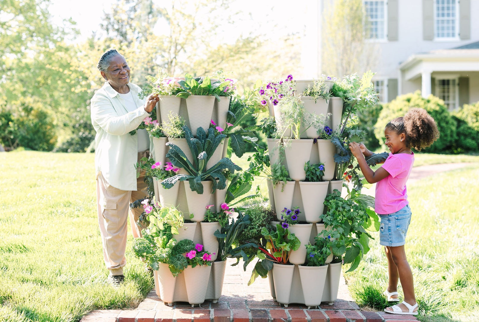 A woman and her grand daughter are tending to their GreenStalk Vertical Planters