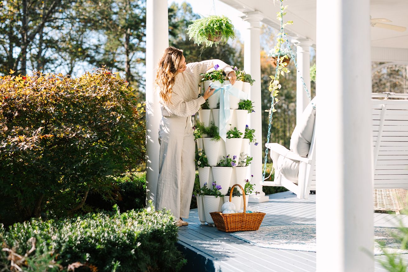 Woman decorating a Snow GreenStalk Vertical Planter for the holidays